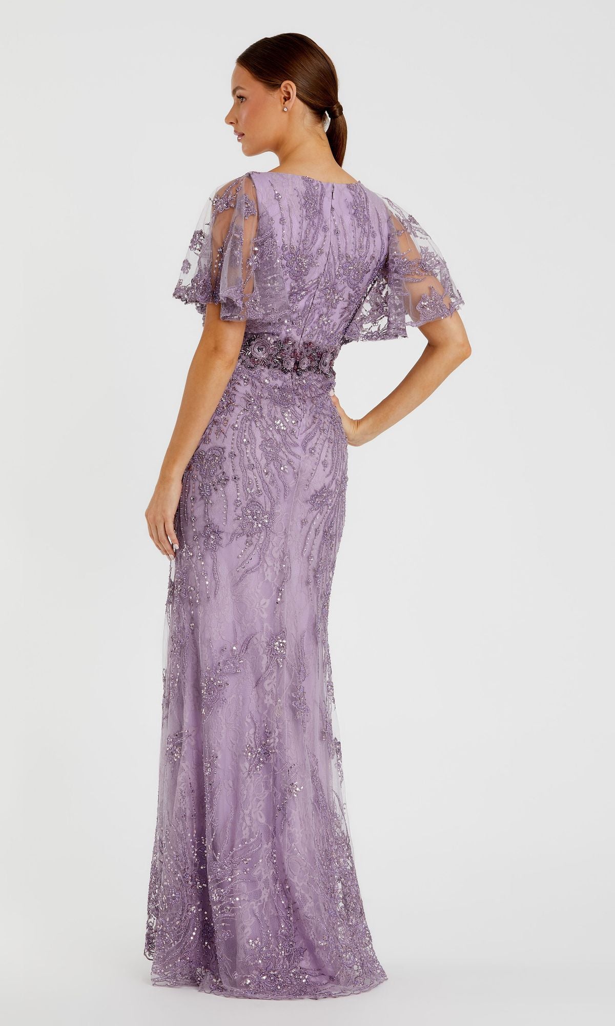A woman in profile wears the Long Formal Dress 67493 by Mac Duggal—a floor-length lilac sequin gown featuring short flutter sleeves and a fitted waist—posing against a plain white background.